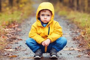 A little boy sits alone on a path, looking sad photo