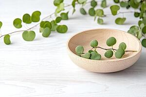 Natural eucalyptus sprigs in a wooden bowl on a white surface photo