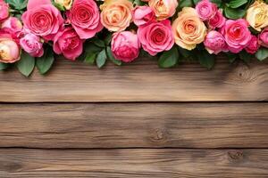 A horizontal border of various shades of pink and peach roses on a rustic wooden background photo