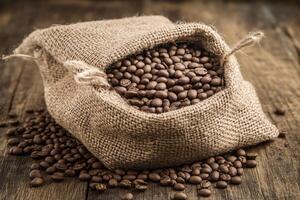 Roasted coffee beans spilling from burlap sack photo