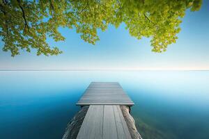 Tranquil lake dock at dawn. Lush foliage frames a serene dock over glassy water photo