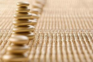 Golden stones balanced in a precise row on a textured surface photo