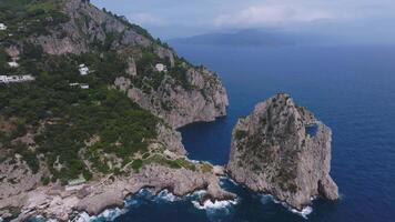 Aerial view of Capri, Italy, showing cliffs with greenery, a white building, rocky islets, and smooth camera motion along the coastline. video