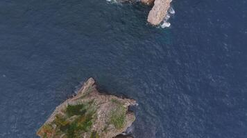 Aerial view of Capri's rugged cliffs, deep blue sea, and crashing waves. The camera moves smoothly, showcasing rock formations and coastal greenery. video