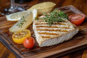 Grilled fish fillet with lemon, potatoes and cherry tomatoes photo
