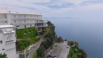 Aerial view of the Amalfi coastline in Italy, showing cliffs, rooftops, a pergola, and boats leaving trails on the serene blue sea. video