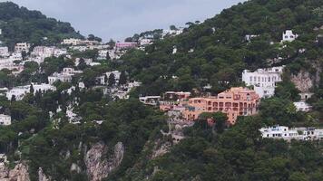 Aerial view of Capri, Italy, showing white and pastel buildings on a hillside. The camera pans over cliffs, greenery, and Mediterranean architecture. video