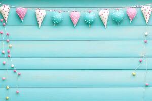Pastel-colored decorations, cone-shaped, and heart-shaped, hang from a light teal wooden surface photo