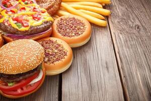 Assorted burgers and fries on a wooden surface photo