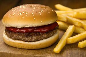 A hamburger and french fries on a wooden cutting board photo