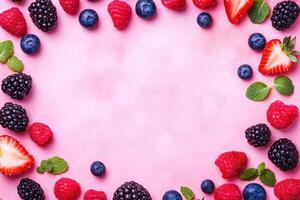 Fresh berries arranged in a frame on a pink background photo