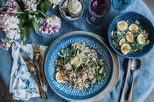 Elegant pasta dish served on a table setting with flowers and wine photo