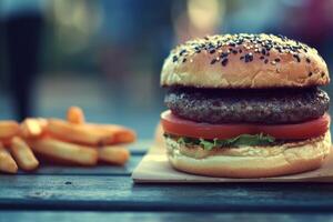 Gourmet burger and fries on a wooden table photo