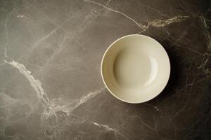 Empty, round, white bowl on dark gray marble surface photo