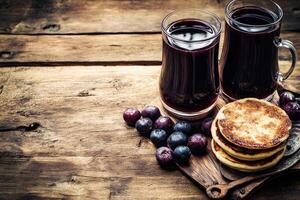 Dark berry drink and pancakes on rustic wood photo