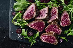 Slices of grilled steak with fresh greens and berries photo