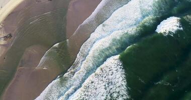drone top down view aerial footage flying over a beach shore water, surf and foam day. Background texture summer sport concept video