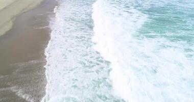 drone top view aerial footage flying over a beach shore water, surf and foam day. Background texture summer sport concept video