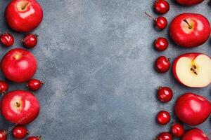 Red apples and berries arranged on a gray surface photo