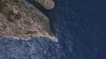 Aerial view of Capri's rugged cliffs, rocky outcrops with vegetation, and deep blue Mediterranean waters, captured with smooth sweeping motion. video