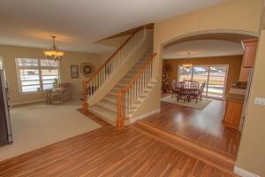 Open-concept home interior, featuring a staircase, dining area, and living space photo