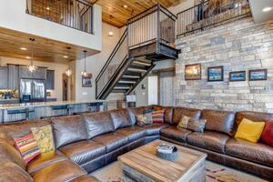 Rustic modern mountain home interior. Large sectional couch, stone fireplace, and open concept living space photo