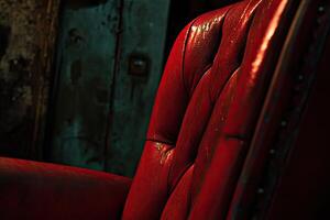 Red leather armchair detail in a dimly lit room photo