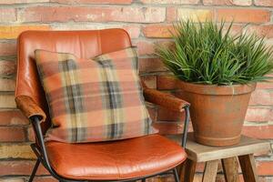 Rustic leather chair with plaid throw pillow and plant photo