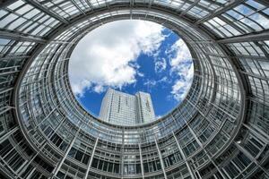 Circular architectural design, looking up to a clear blue sky with clouds and buildings photo