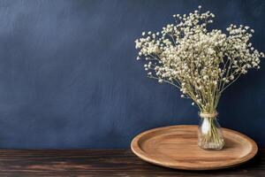 A simple bouquet of dried white flowers in a clear glass vase on a wooden tray photo