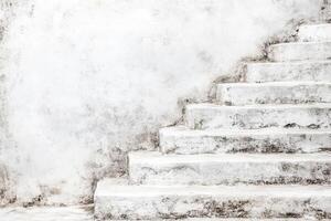 Aged white stone steps against a weathered wall photo