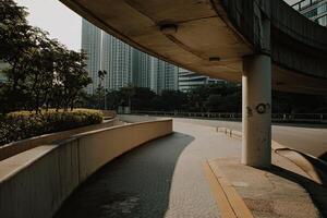 Urban underpass pathway beneath modern buildings. Lush greenery and sunlight filtering through the structure photo