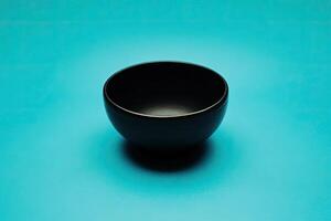 Empty black bowl on a teal background photo