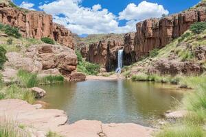 Scenic waterfall cascading into a tranquil pool, surrounded by red rock cliffs photo