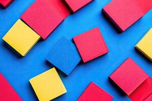 Vibrant, square sticky notes scattered on a vibrant blue background photo