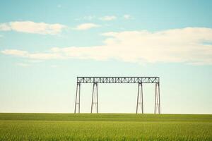 A metal bridge spans a grassy field under a light blue sky photo