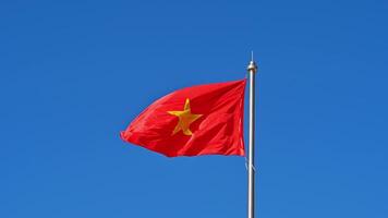 Vietnamese flag with a yellow star on flagpole flutters in the wind on the background of blue sky in Vietnam video