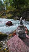A cairn of small stones against the background of a slowly flowing mountain river. video