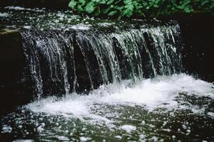 Small waterfall cascading over dark stones photo