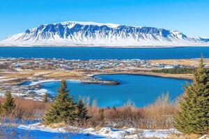 Panoramic view of a Icelandic village nestled by a fjord, snow-capped mountains in the background photo