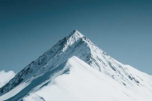 Snow-capped mountain peak against a clear blue sky photo