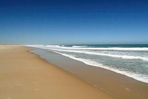 Vast sandy beach meets the ocean photo