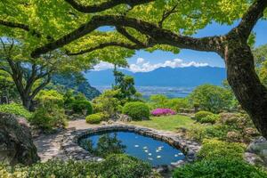 Serene Japanese garden with pond, under a canopy of vibrant green trees, showcasing a tranquil vista of distant mountains and cityscape photo
