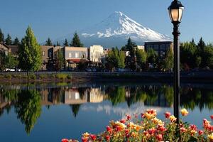 Peaceful town reflecting in a calm pond, majestic mountain backdrop photo