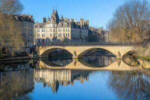 Picturesque stone bridge over calm river, reflecting historic buildings photo