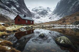 Rustic cabin nestled amidst snowy mountains, reflecting in a tranquil pond photo