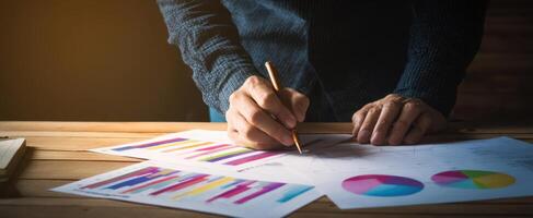 The person analyzing colorful charts and graphs on a wooden desk. photo