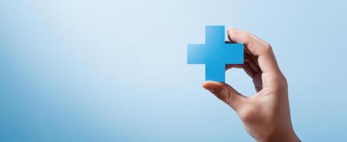 The blue cross symbol held in hand representing healthcare and support. photo