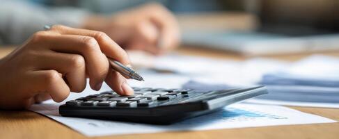 The focused hand calculating financial figures with a calculator and pen. photo