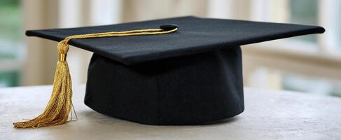 The black graduation cap with golden tassel on a marble table photo
